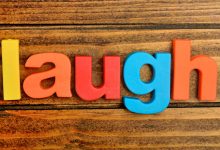 The word laugh spelled out in letters on a wooden table
